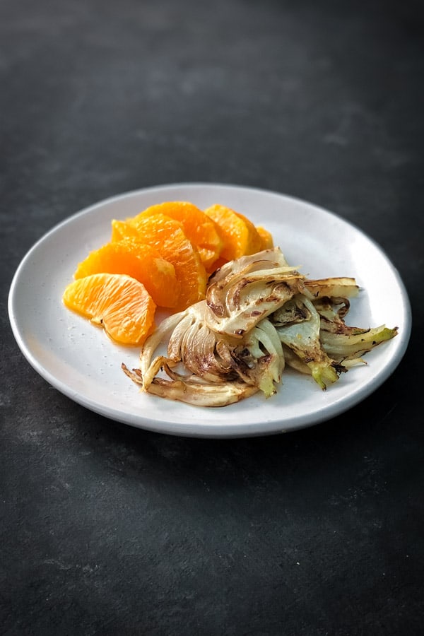 Orange slivers and charred fennel on white plate