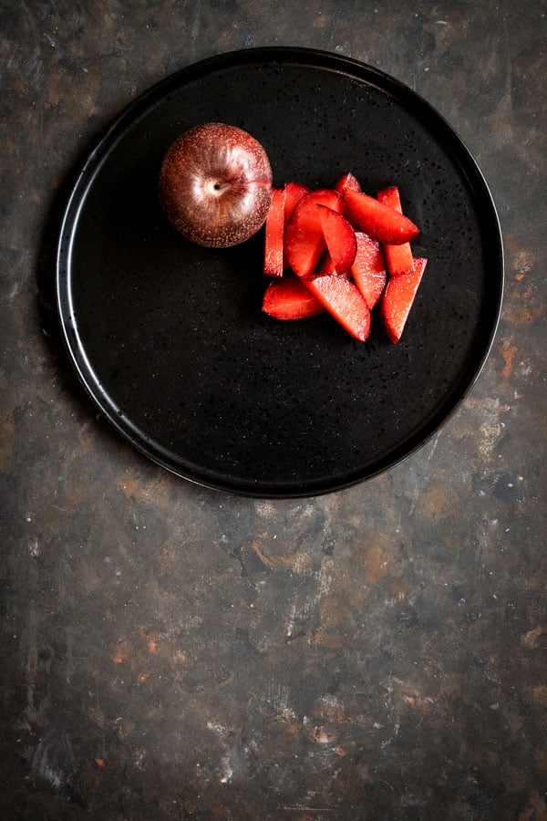 Sliced and whole black plums for red fruit salad