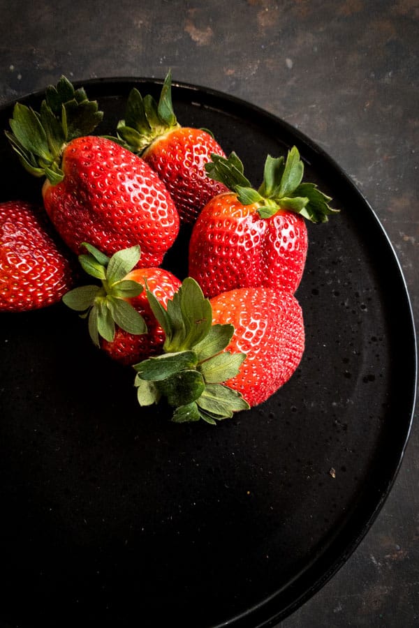 Strawberries on black plate for red fruit salad