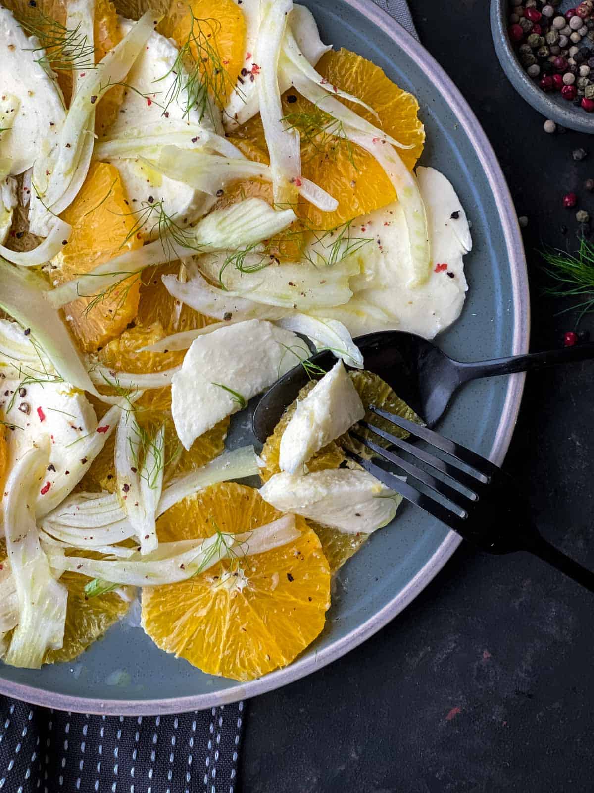 Orange Fennel Salad on a blue plate with black fork and spoon