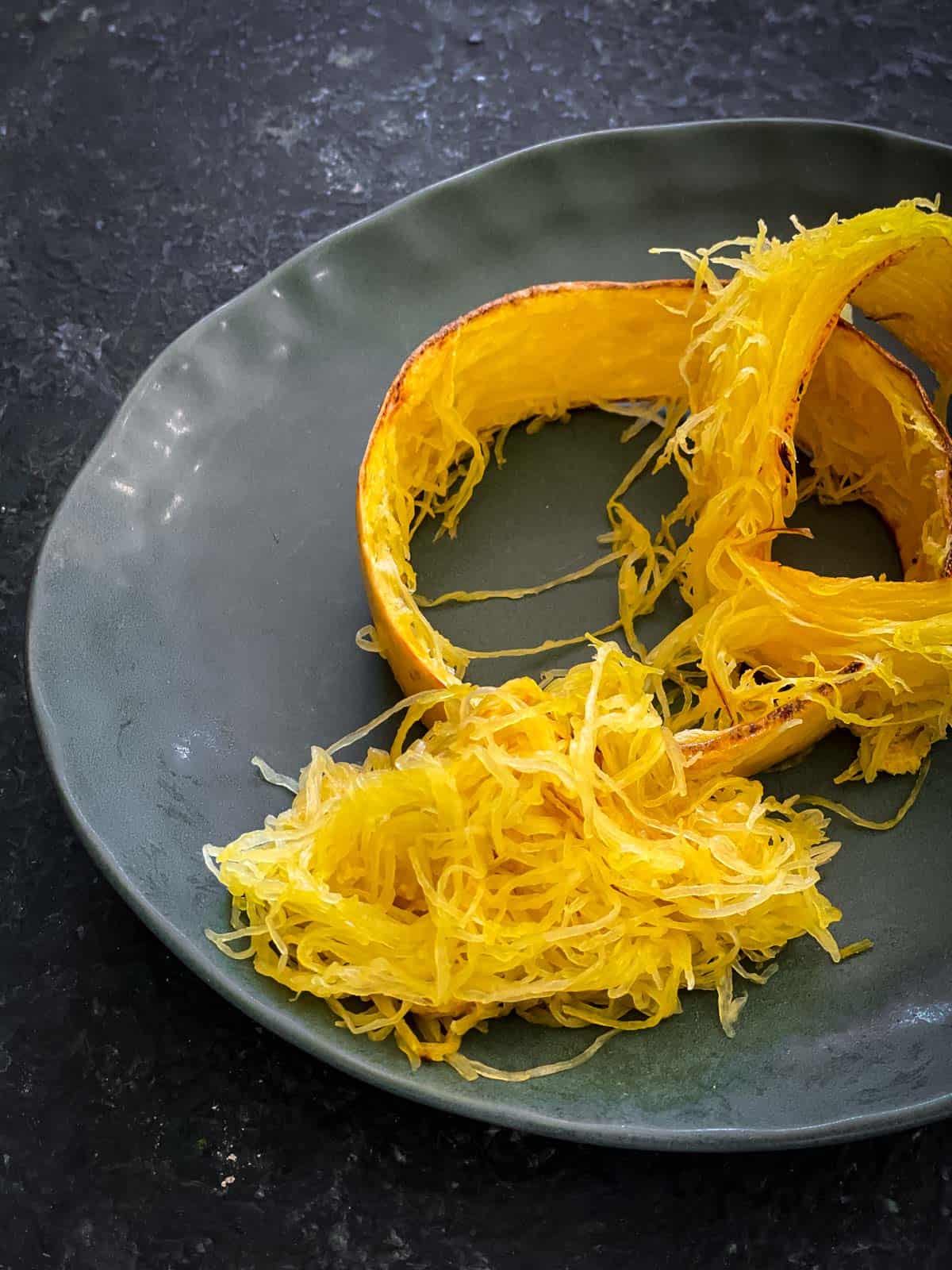 Baked spaghetti squash strands on a green plate