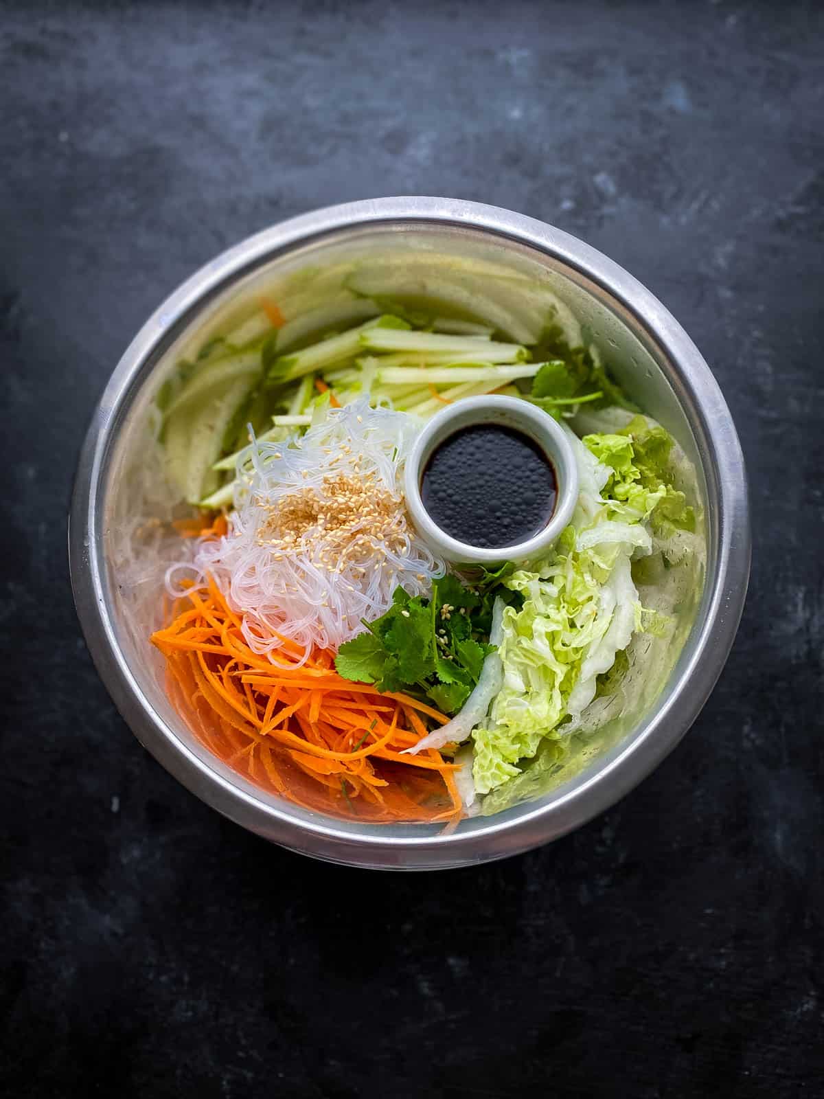 Mixing Glass Noodle Salad with Sticky Tofu ingredients in a mixing bowl