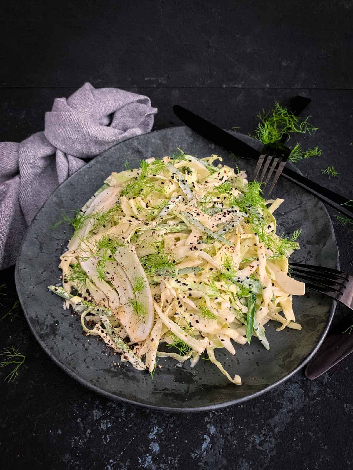 Spicy Keto Coleslaw on a black plate with plate cutlery