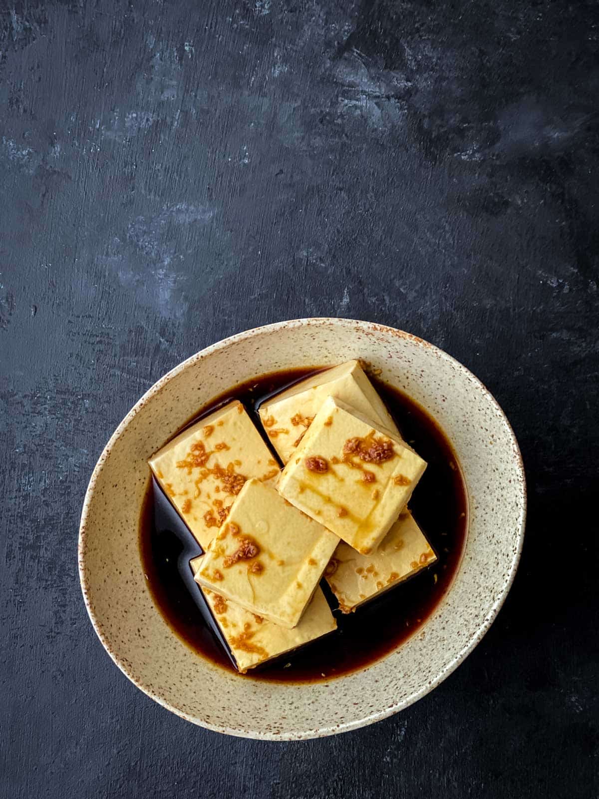 Sticky tofu in marinade in an earthen bowl