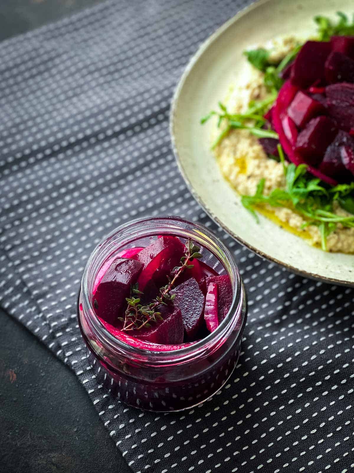 Pickled beets in a small jar served with with chickpea mash