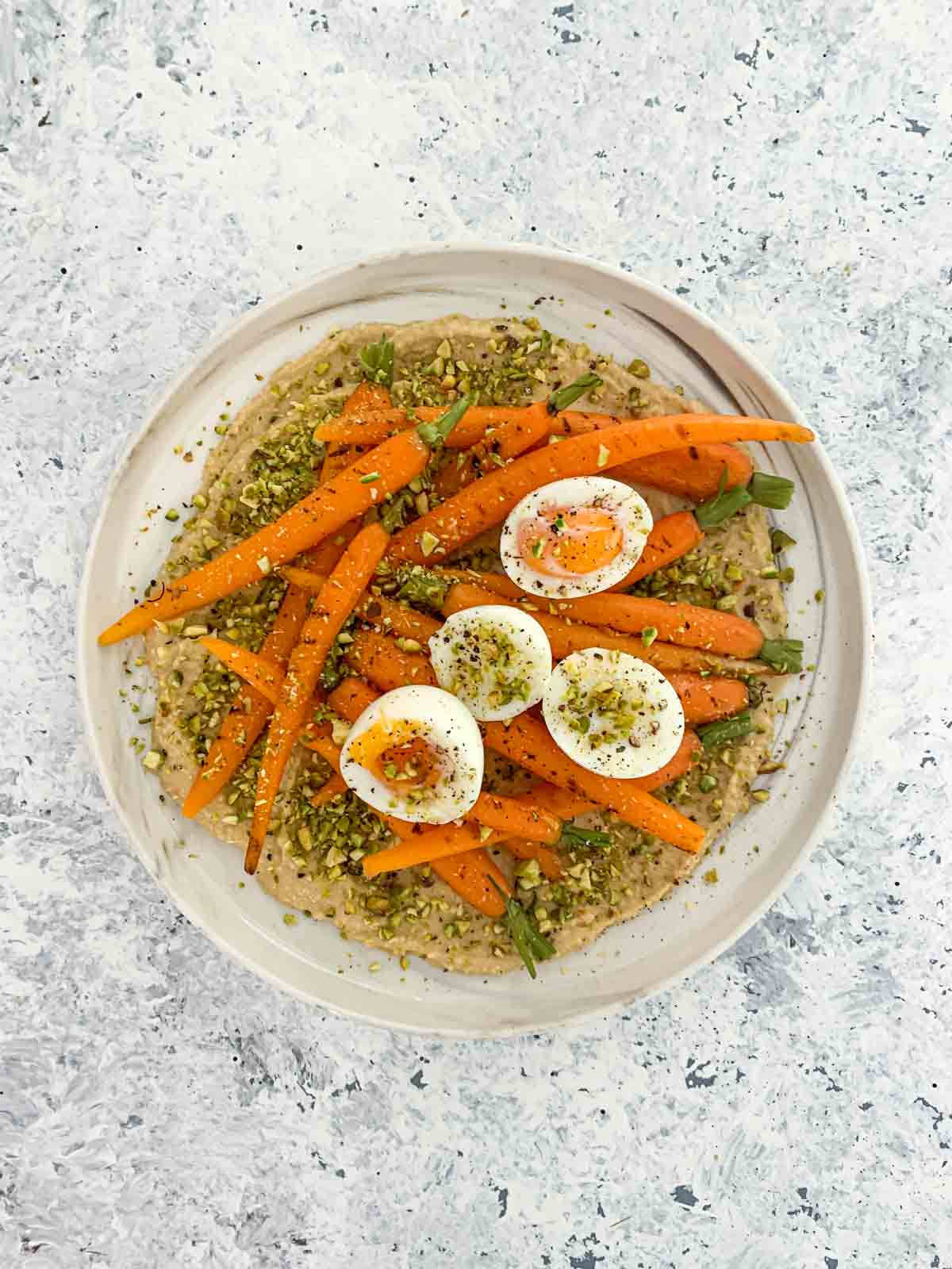 Salad of Dutch Carrots, Hummus and Soft-Boiled Eggs on a white marbled plate