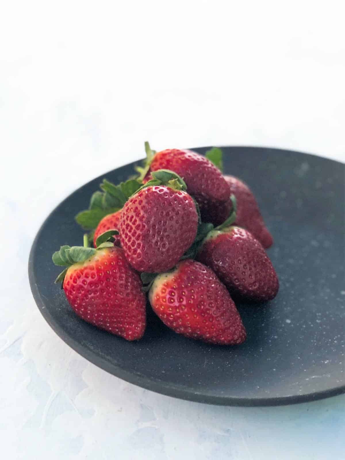 Whole strawberries on a black plate