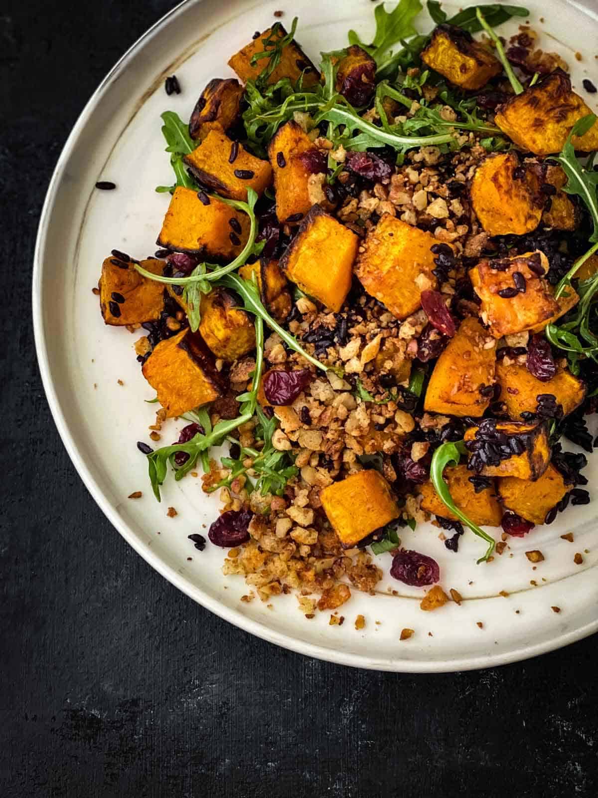 Vegan Salad with Butternut Squash and Cranberries on a white marbled plate