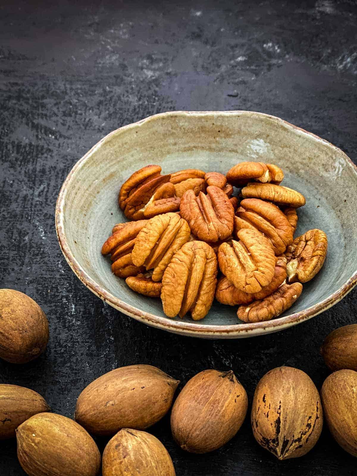 Shelled and de-shelled pecan nuts in an earthen bowl