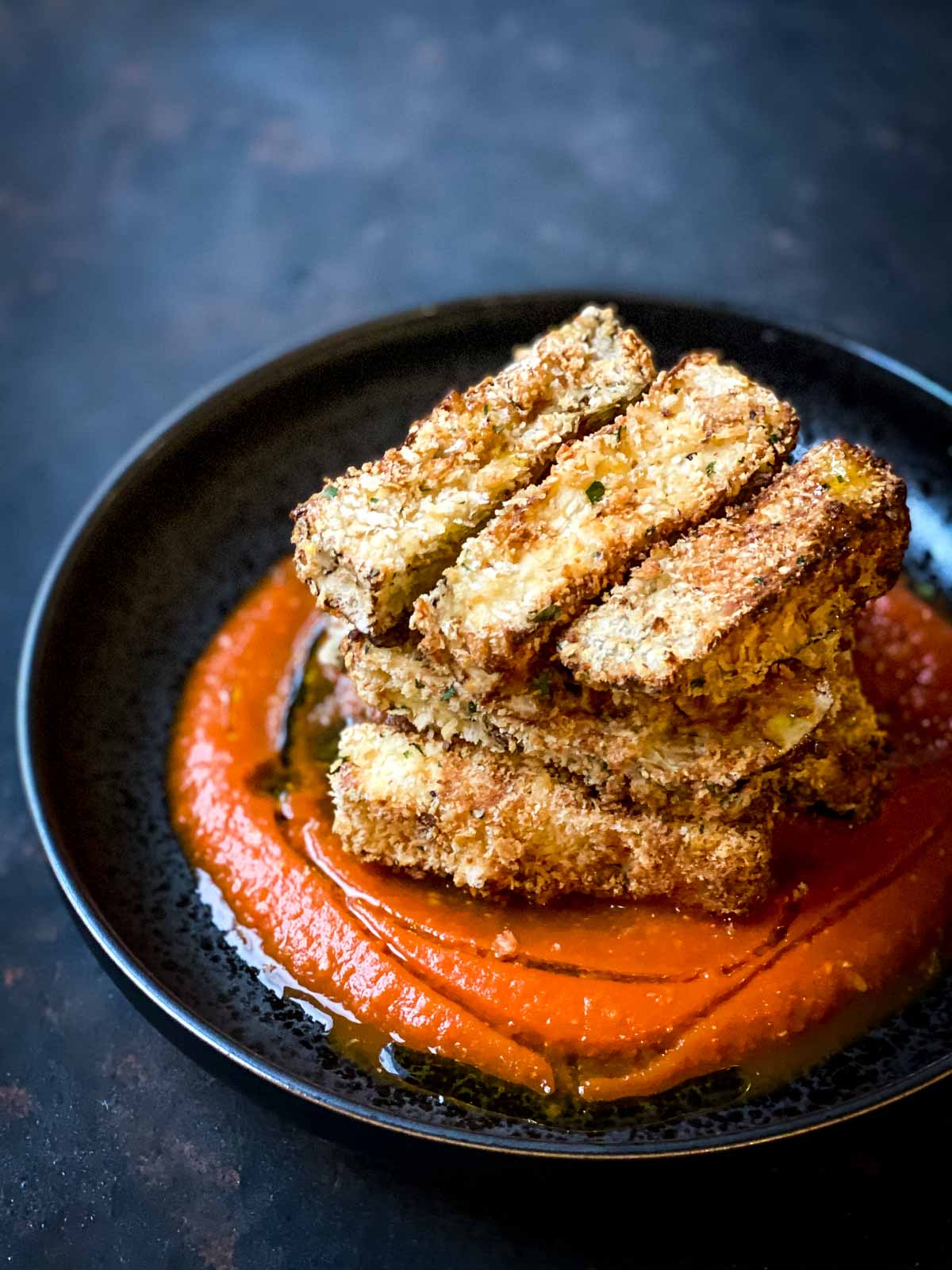 Air Fryer Eggplant with Roasted Red Pepper Sauce in a black shallow bowl