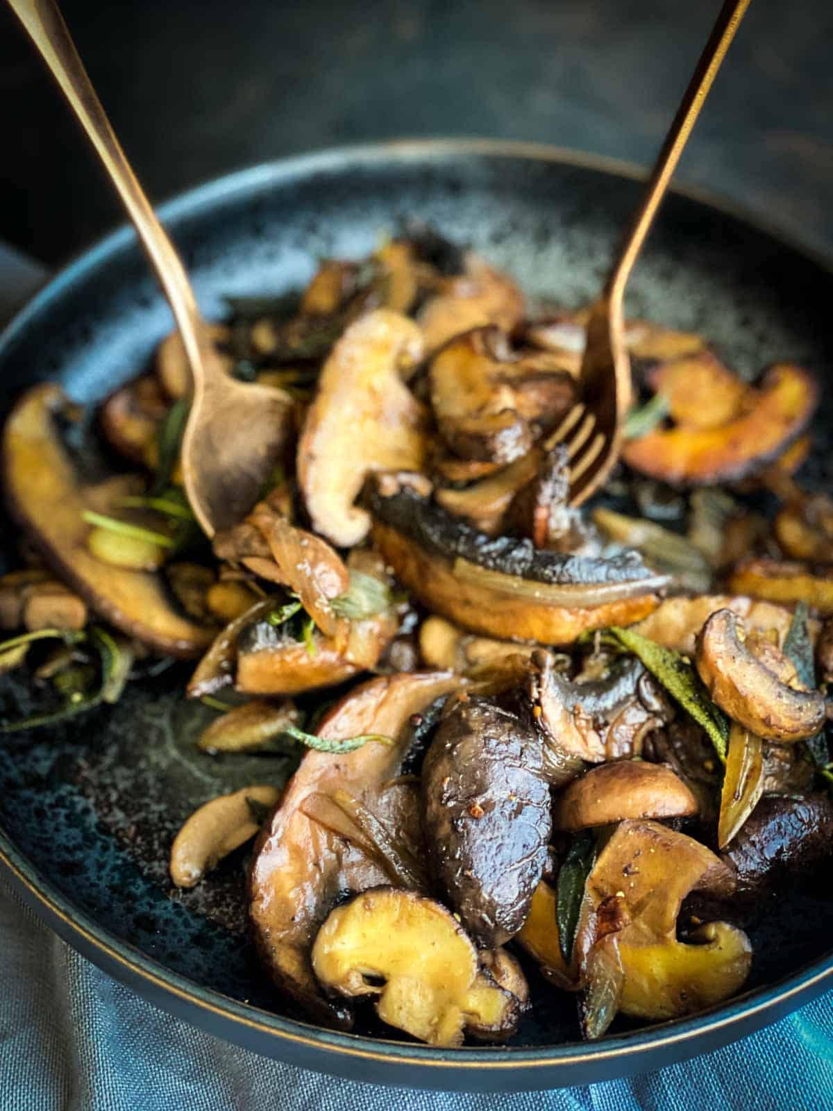 Serving Easy Sautéed Mushrooms with Soy Sage Butter with a fork and spoon