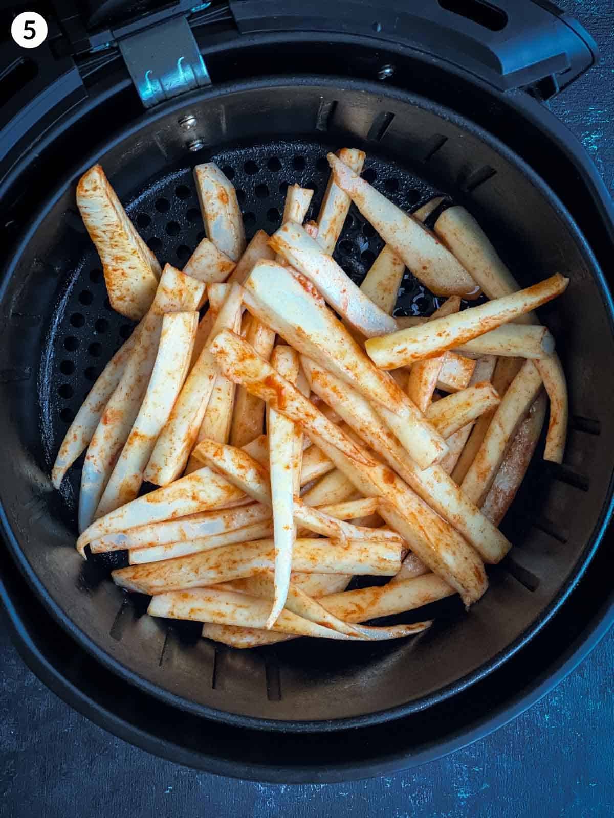 Seasoned parsnips fries in an air fryer basket