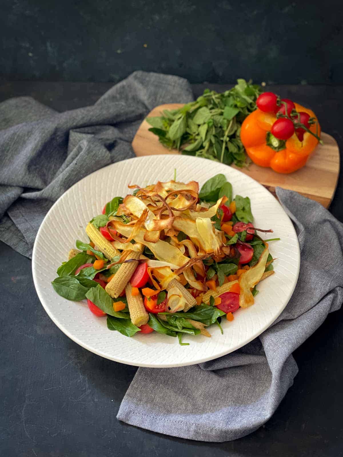 Baby Corn Salad with Crisp Parsnip Ribbons on a white plate with blue napery