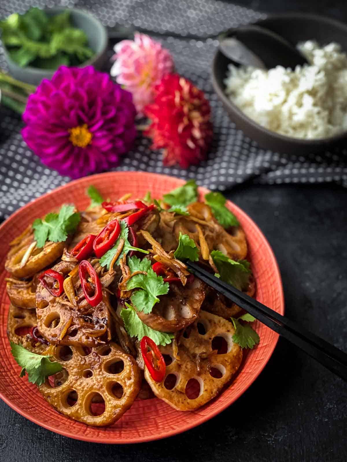 Hot and Sour Stir-Fried Lotus Root served with chopsticks and rice decorated with flowers