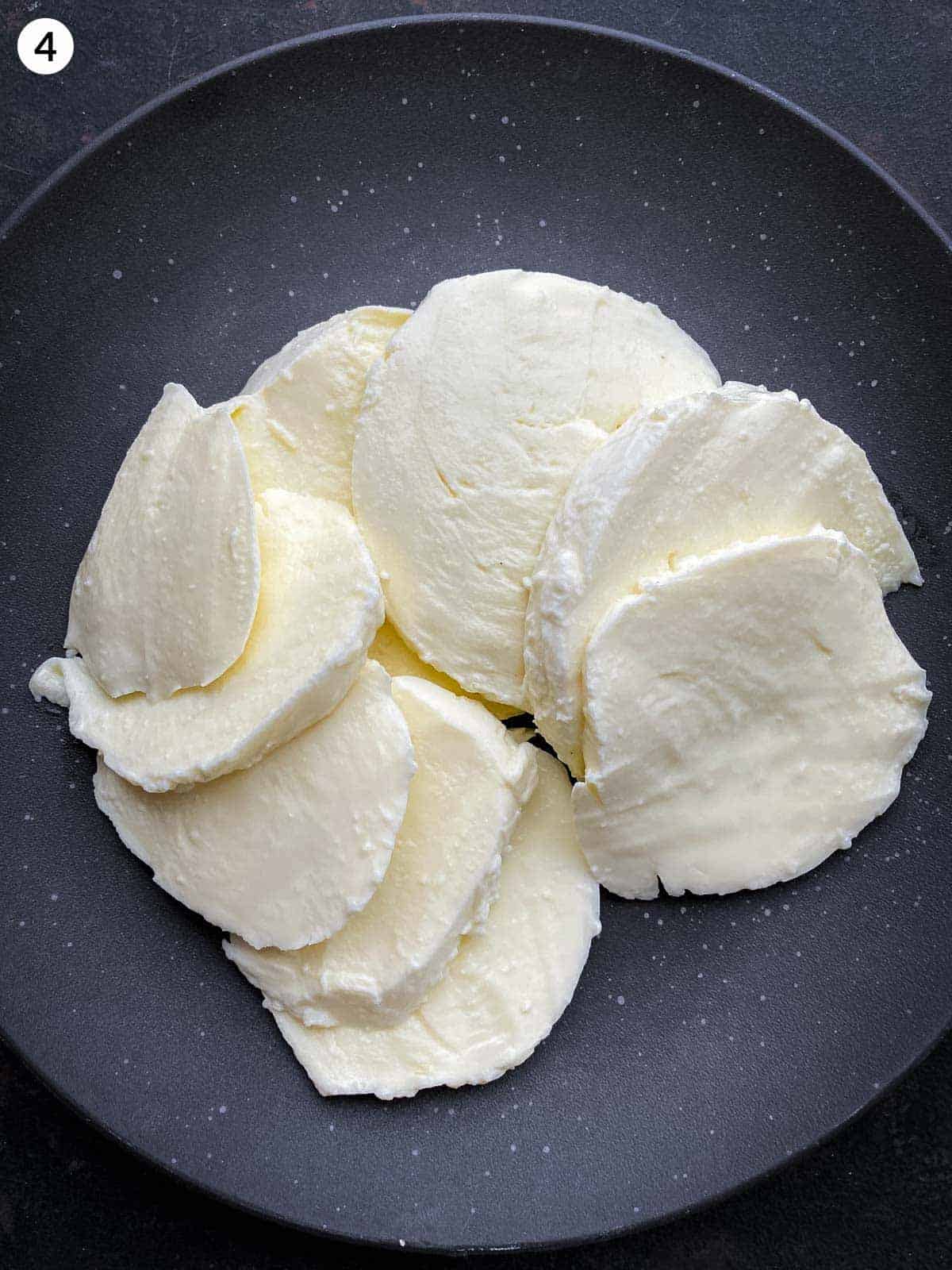 Slices of buffalo mozzarella on a black plate