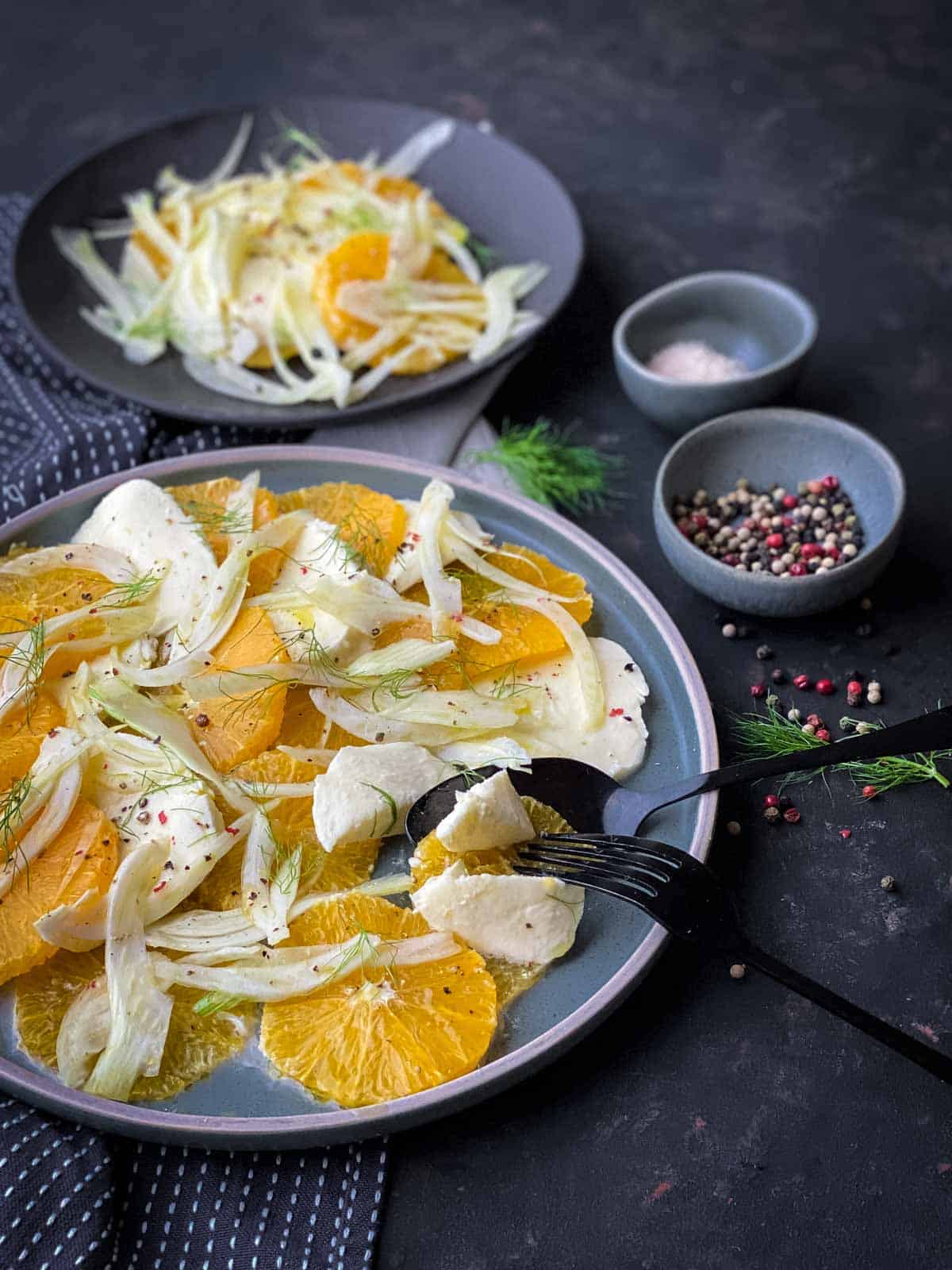 Orange Fennel Salad on a blue plate with black fork and spoon