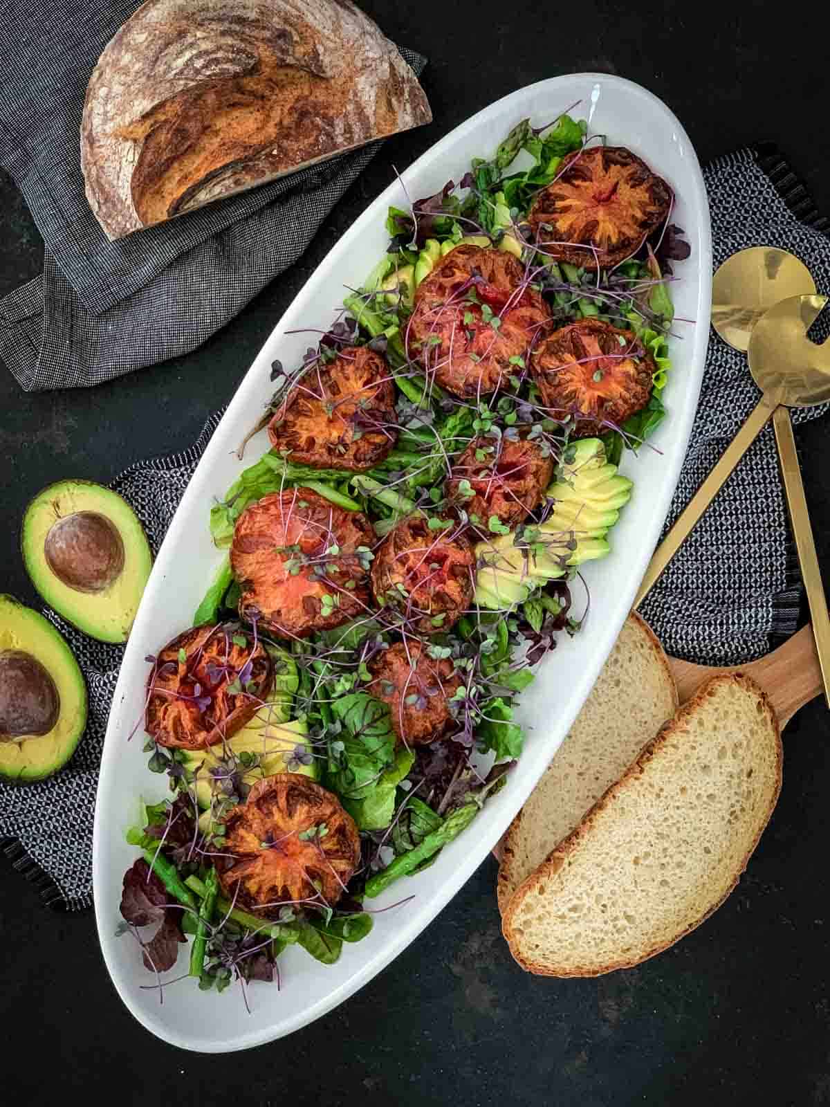 Salad with Heirloom Tomatoes and Asparagus served with bread and a pair of gold salad servers