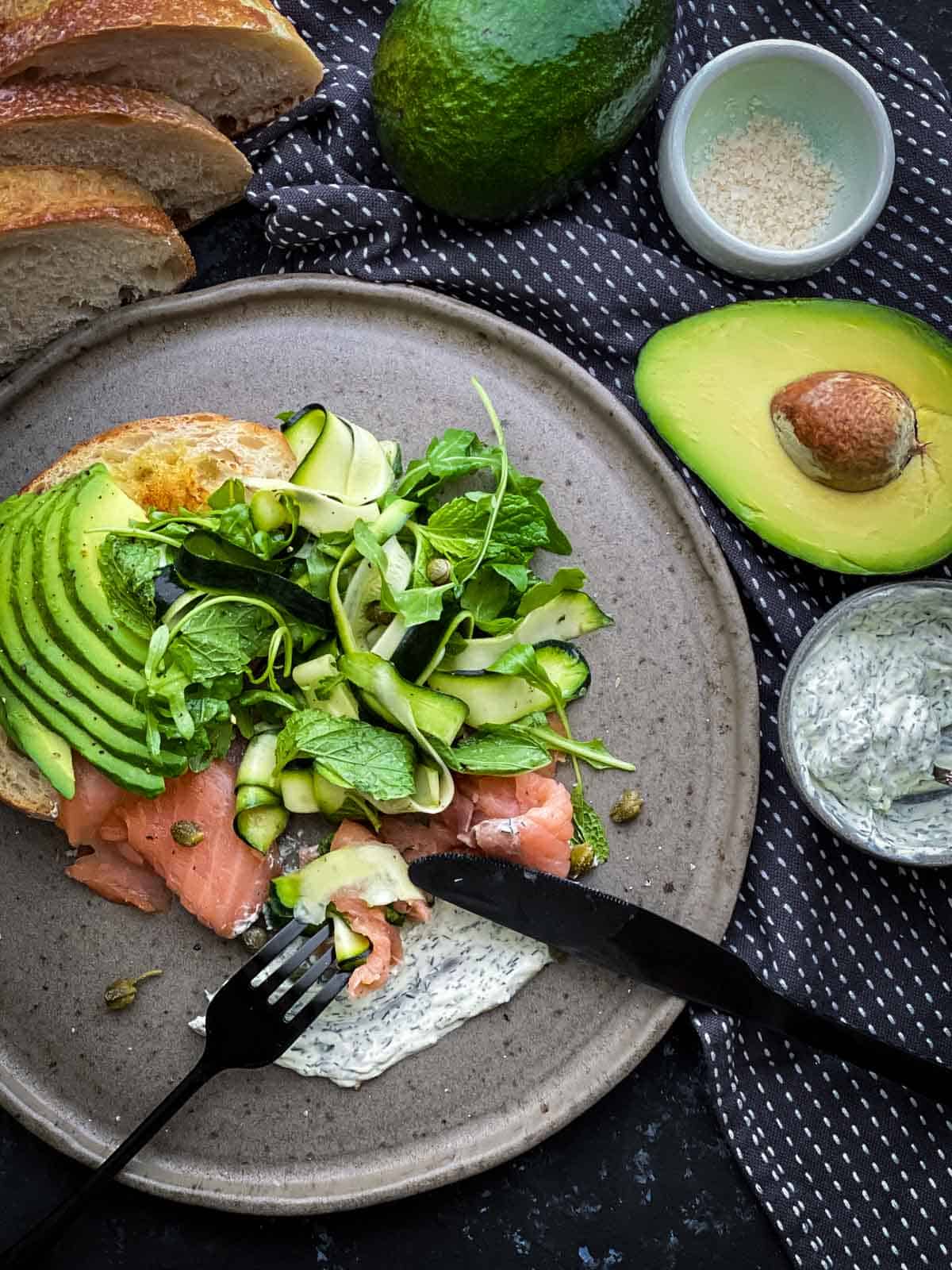 Smoked Salmon Avocado Salad with black cutlery on grey coloured plate