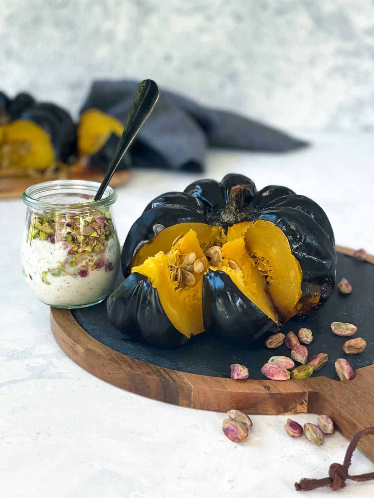 Whole Roasted Heirloom Pumpkin on a wooden board with yoghurt dressing on the side