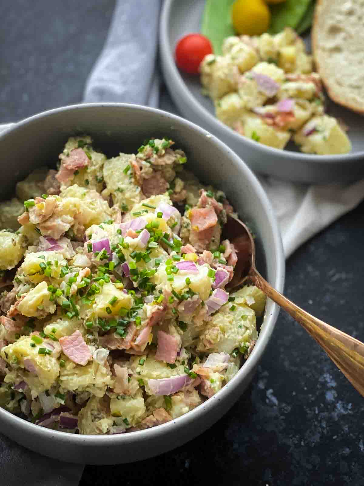 Potato salad in a large grey bowl with a spoon inside