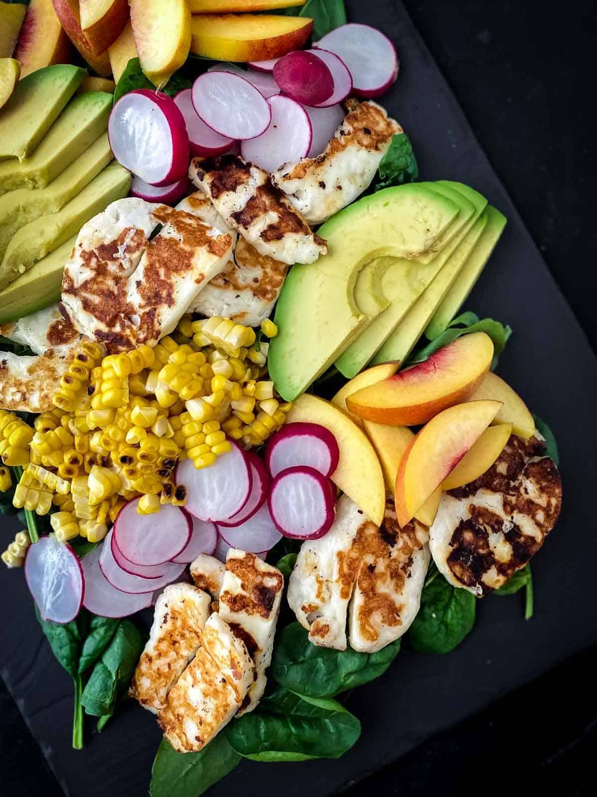 Yellow Nectarine Salad with Grilled Halloumi on a black slate plate
