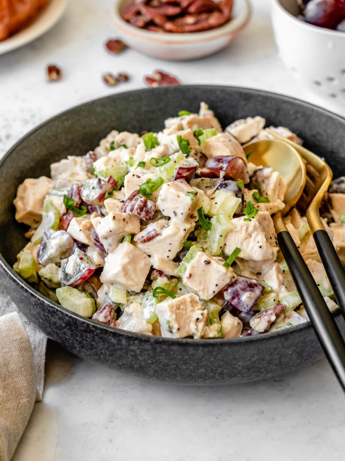 California chicken salad served in a black bowl and black and gold cutlery