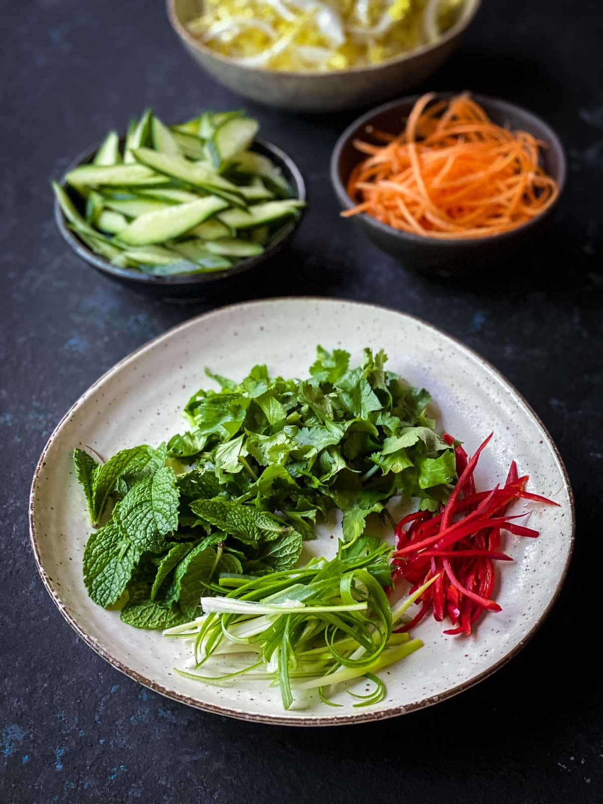 Chopped and sliced Spring onion, chilli, mint and coriander on a brown plate