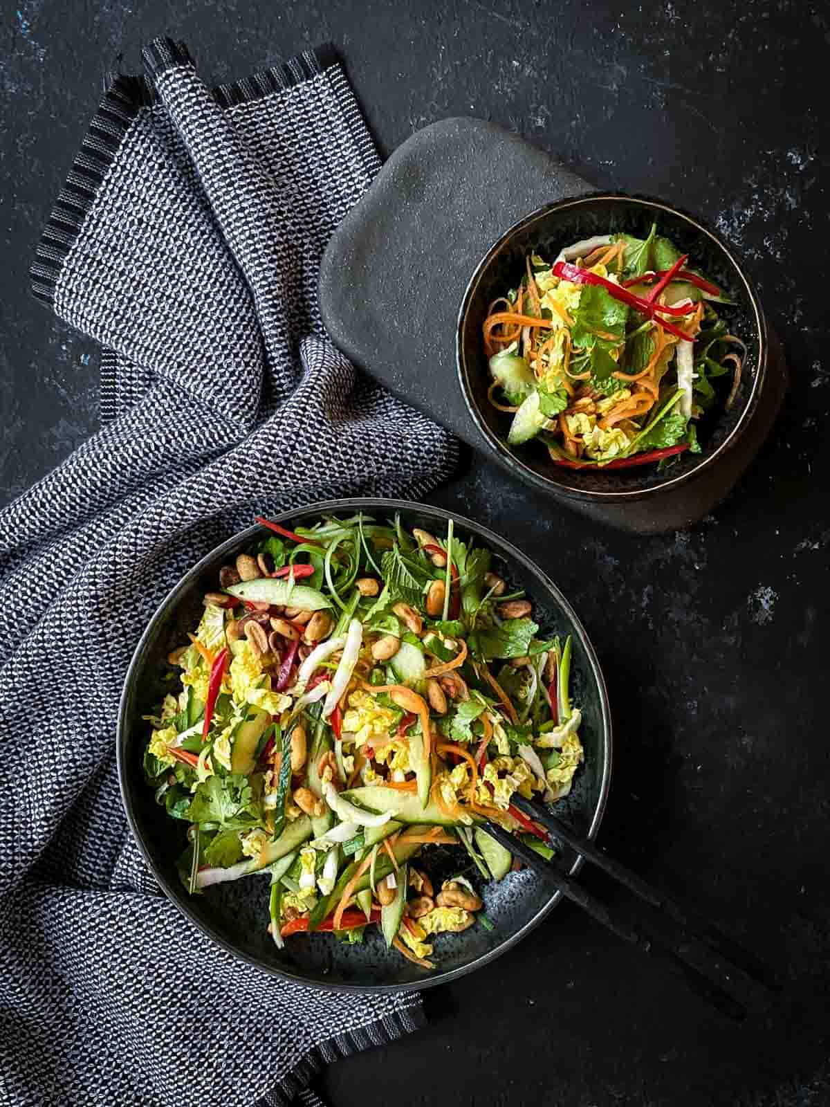 two Chinese Cabbage Salad in grey salad bowls on blue napery