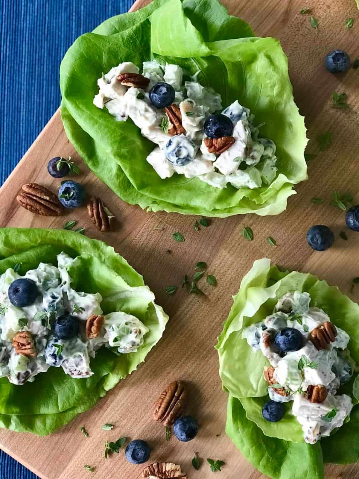 Chicken and blueberry salad served ono lettuce cups on a wooden board