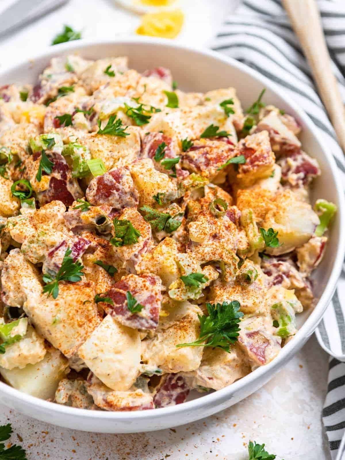 Cajun potato salad served in a white bowl and a striped napkin on the side