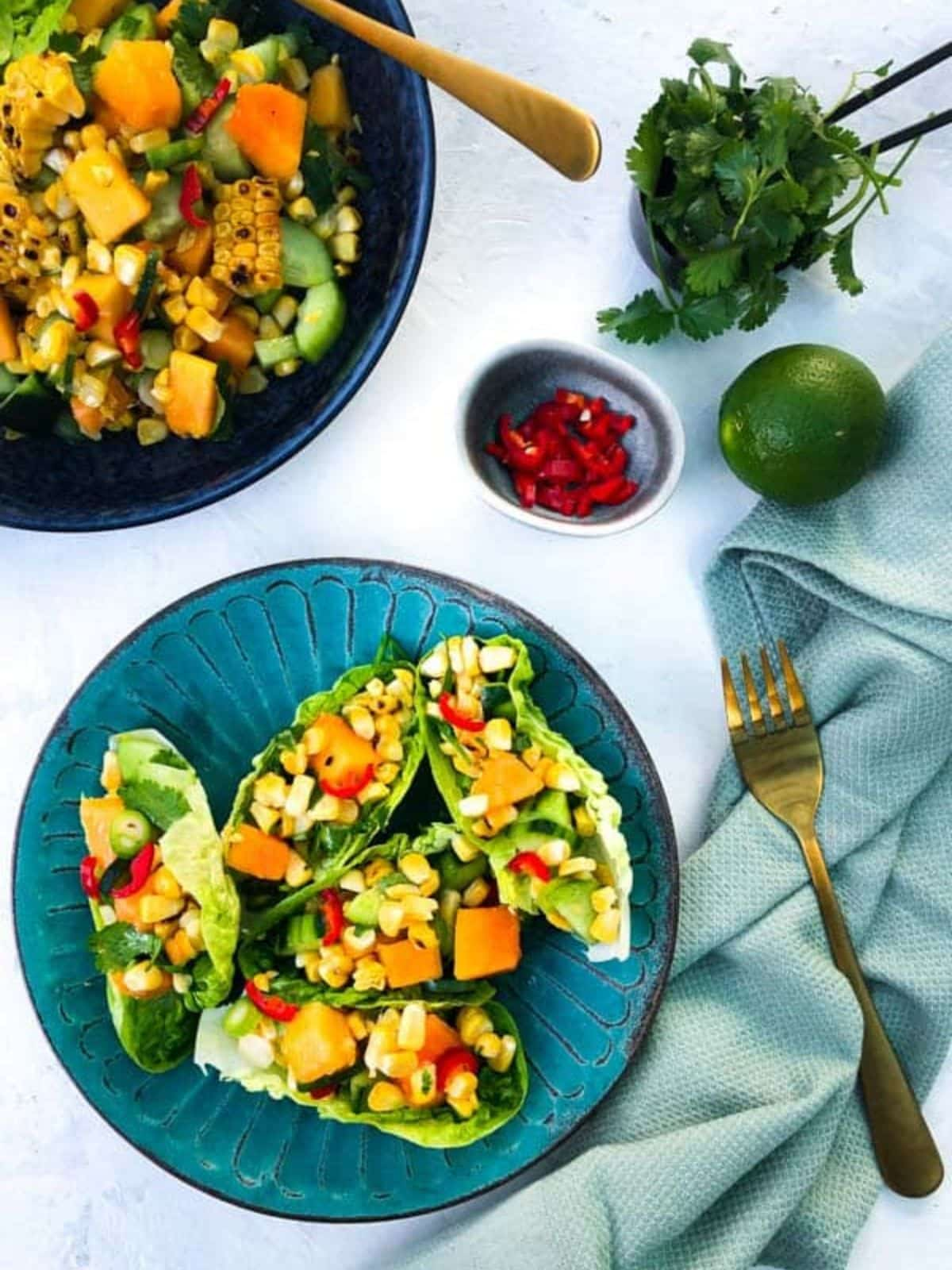 2 serve of chilli charred corn salad in blue plates and gold cutlery