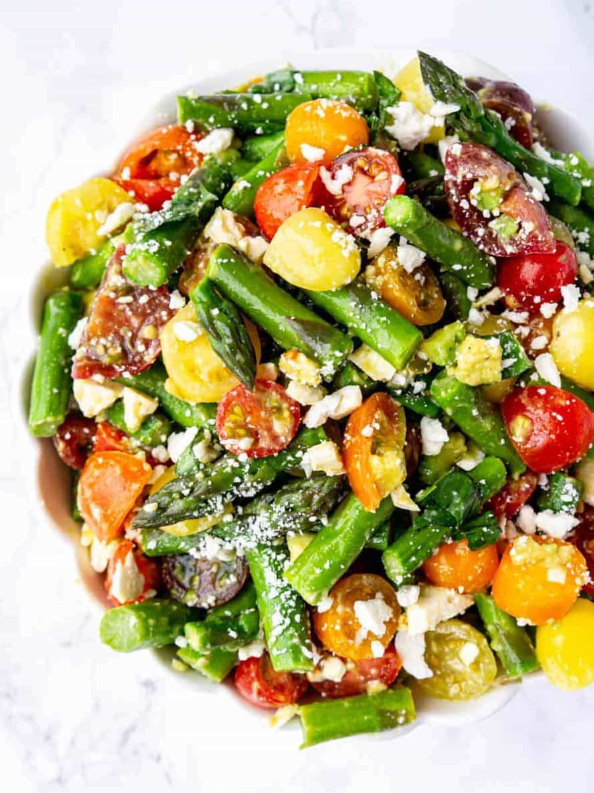 Cold asparagus and tomato salad in a white bowl