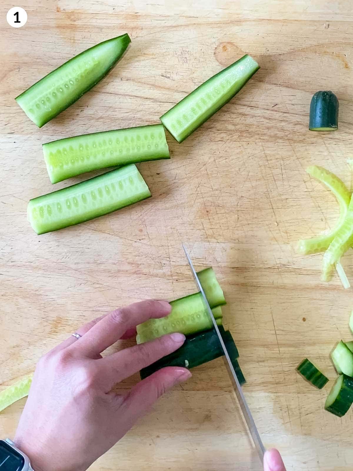 Cutting cucumber with a knife on wooden chopping board