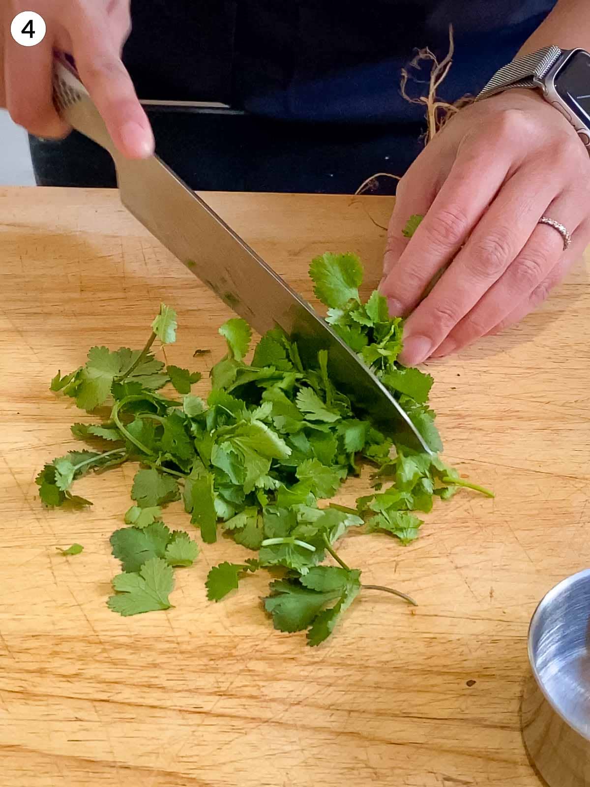 Person in an apron chopping coriander leaves