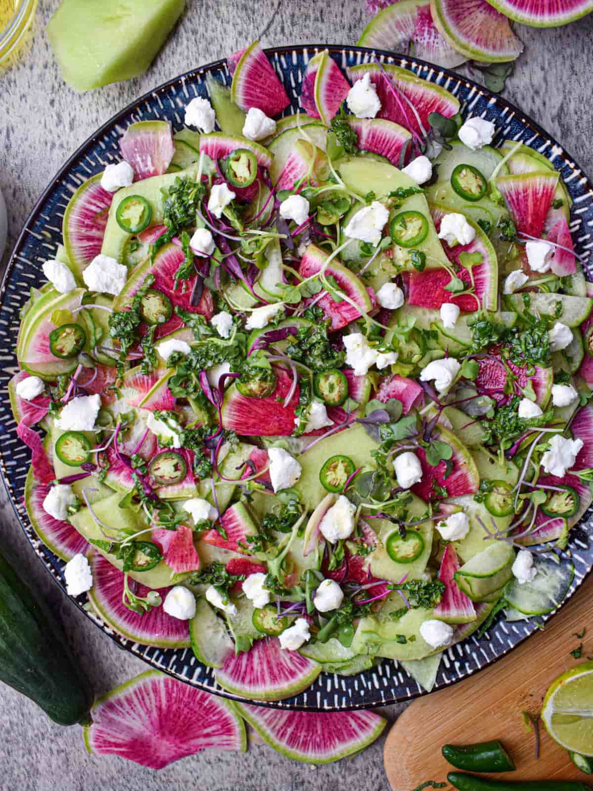 melon cucumber radish salad in a blue and white patterned salad platter surrounded by slices of watermelon radish