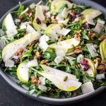 close up of a grey plate filled with pear arugula salad