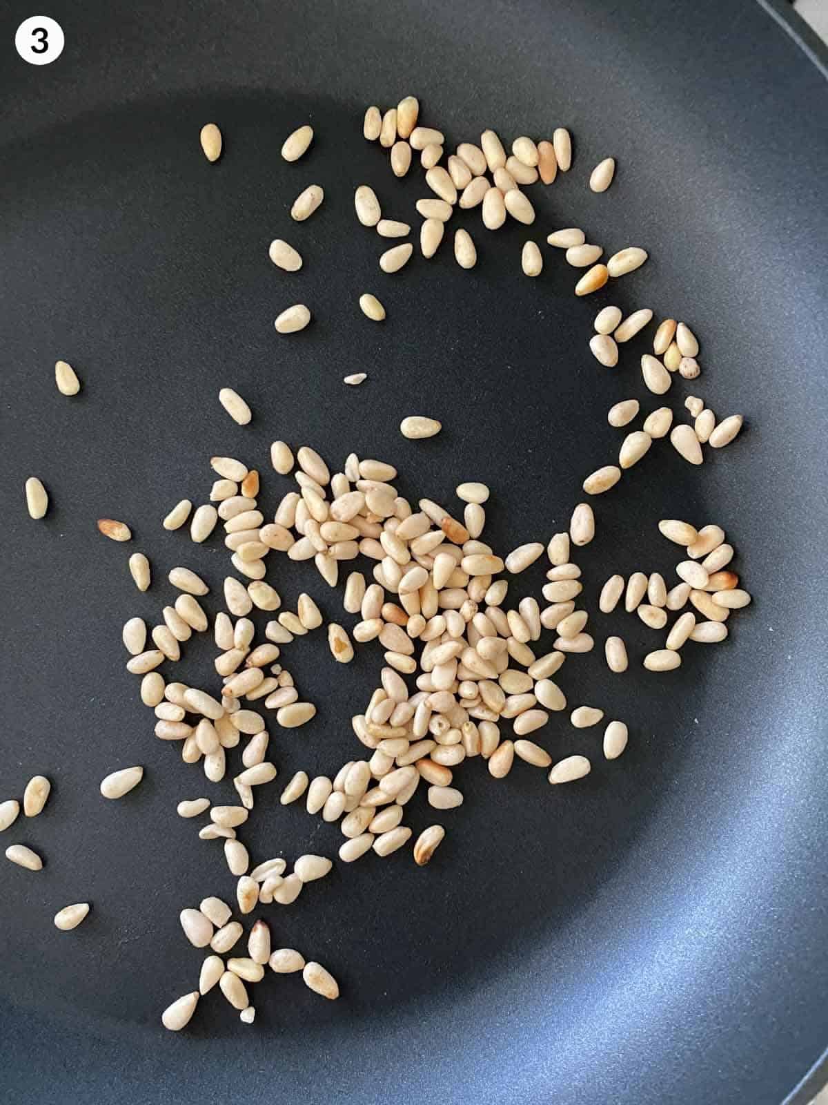 toasted pine nuts in a fry pan