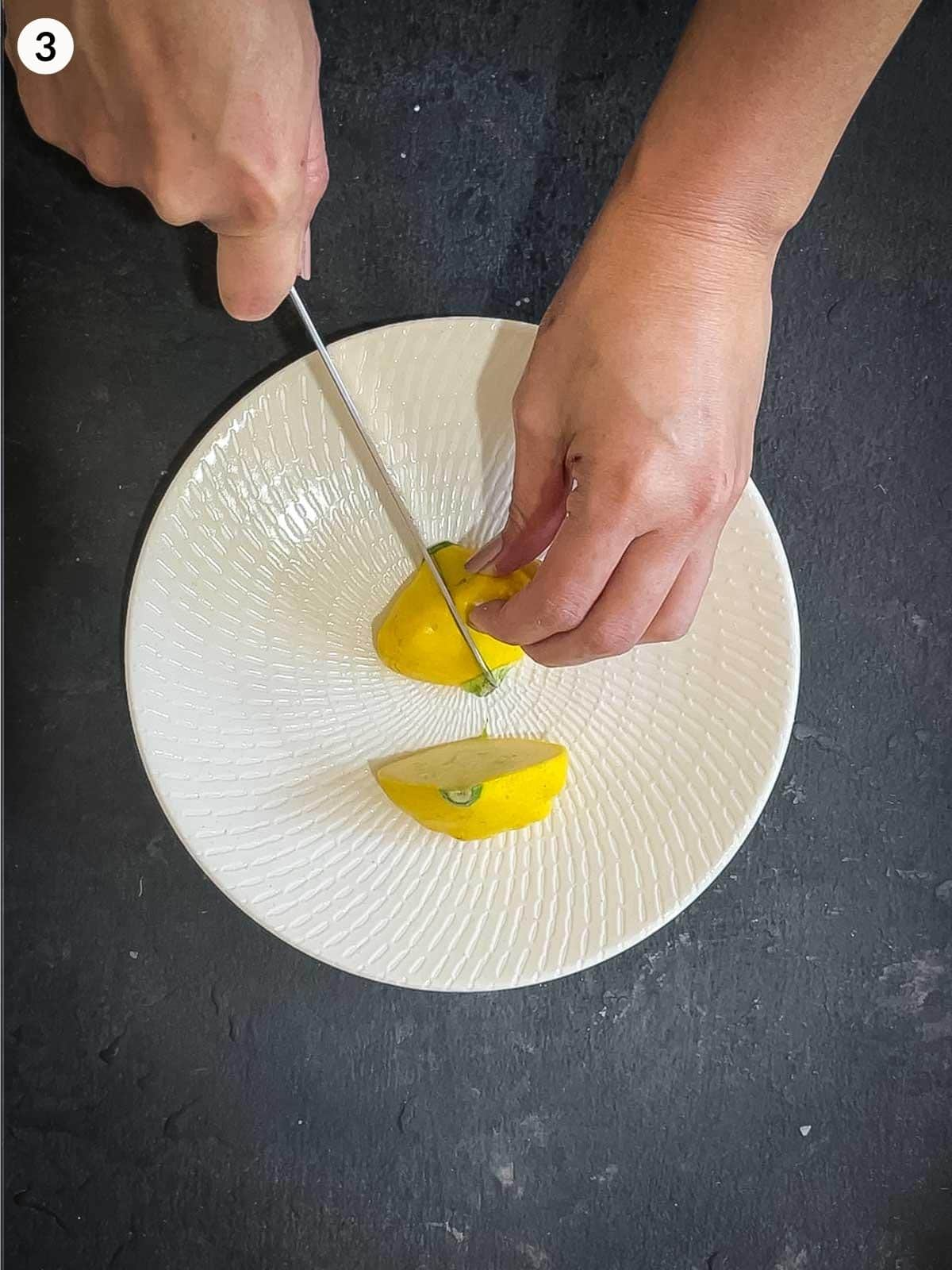 Cutting yellow squash into quarters on a white plate