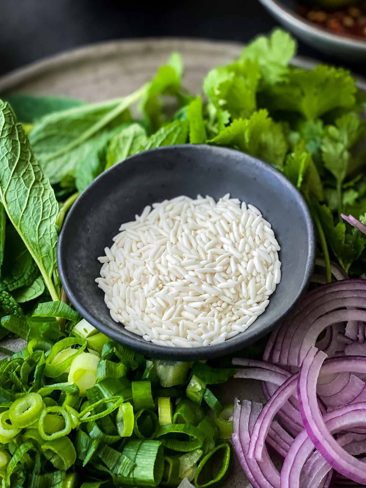 a small plate of glutinous rice on top of a plate of salad ingredients