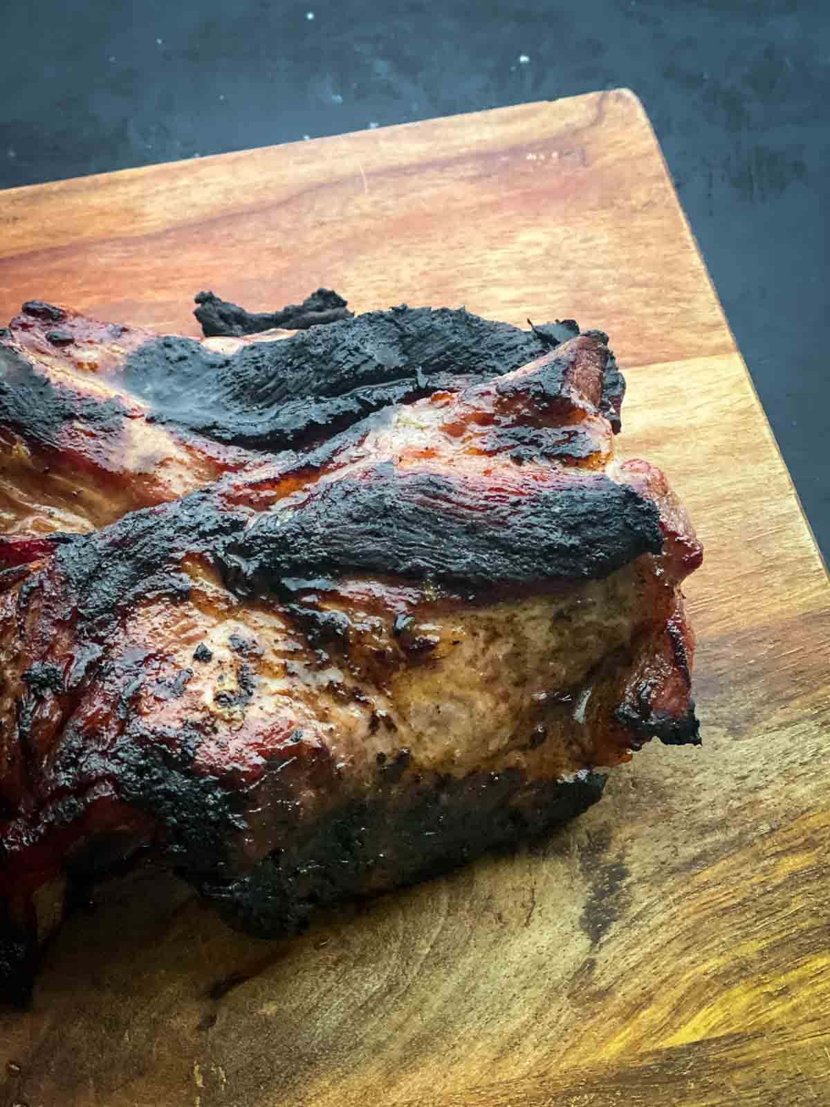 two pieces of grilled pork on a wooden chopping board