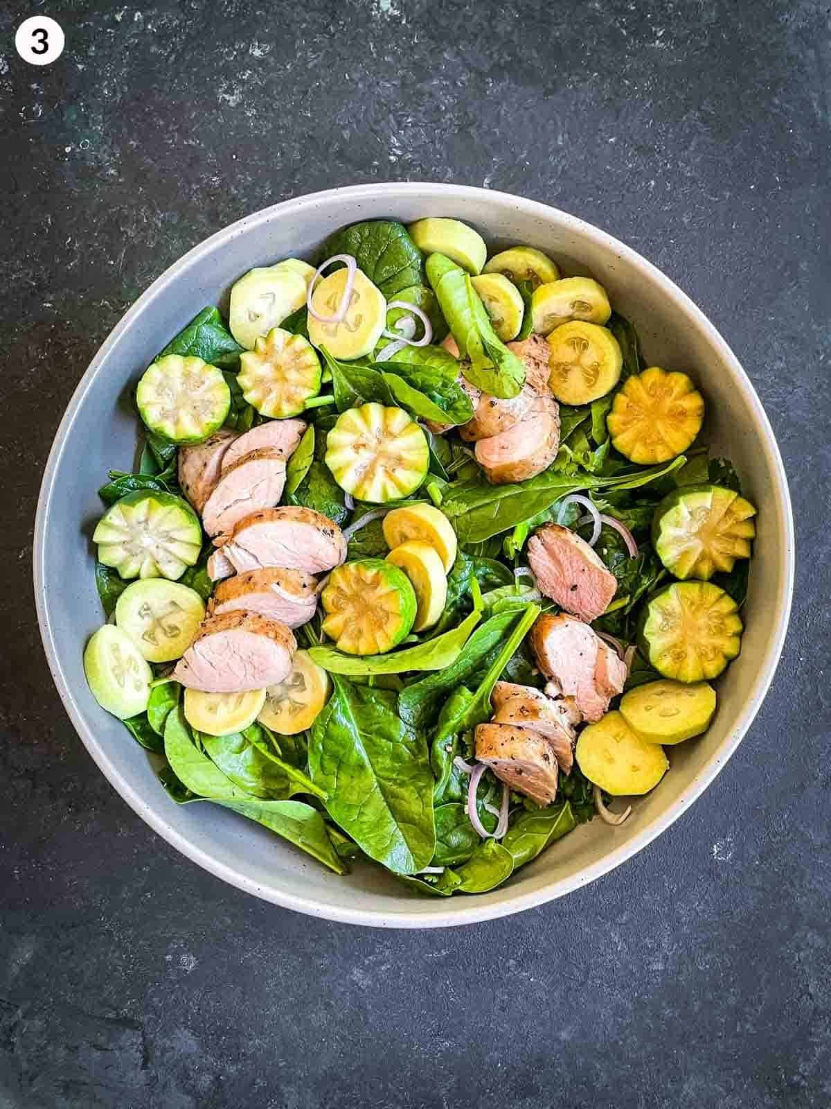 baby spinach leaves, shallots, feijoas and slices of sous vide pork tenderloin in a round bowl