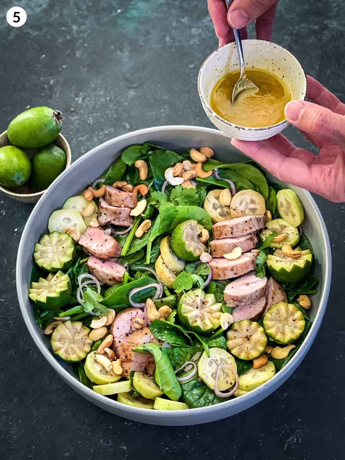 pouring ginger vinaigrette over Sous Vide Pork Tenderloin Salad