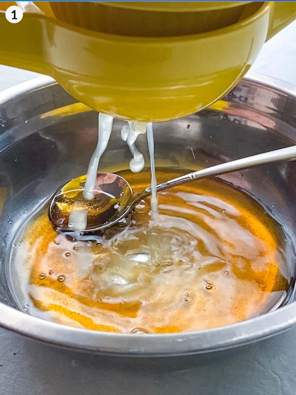 Squeezing lemon in a yellow citrus squeezer over a mixing bowl of salad dessing