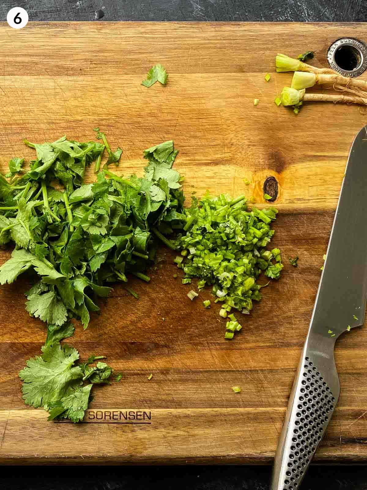roughly chopped cilantro leaves next to finely chopped cilantro stems on a wooden chopping board