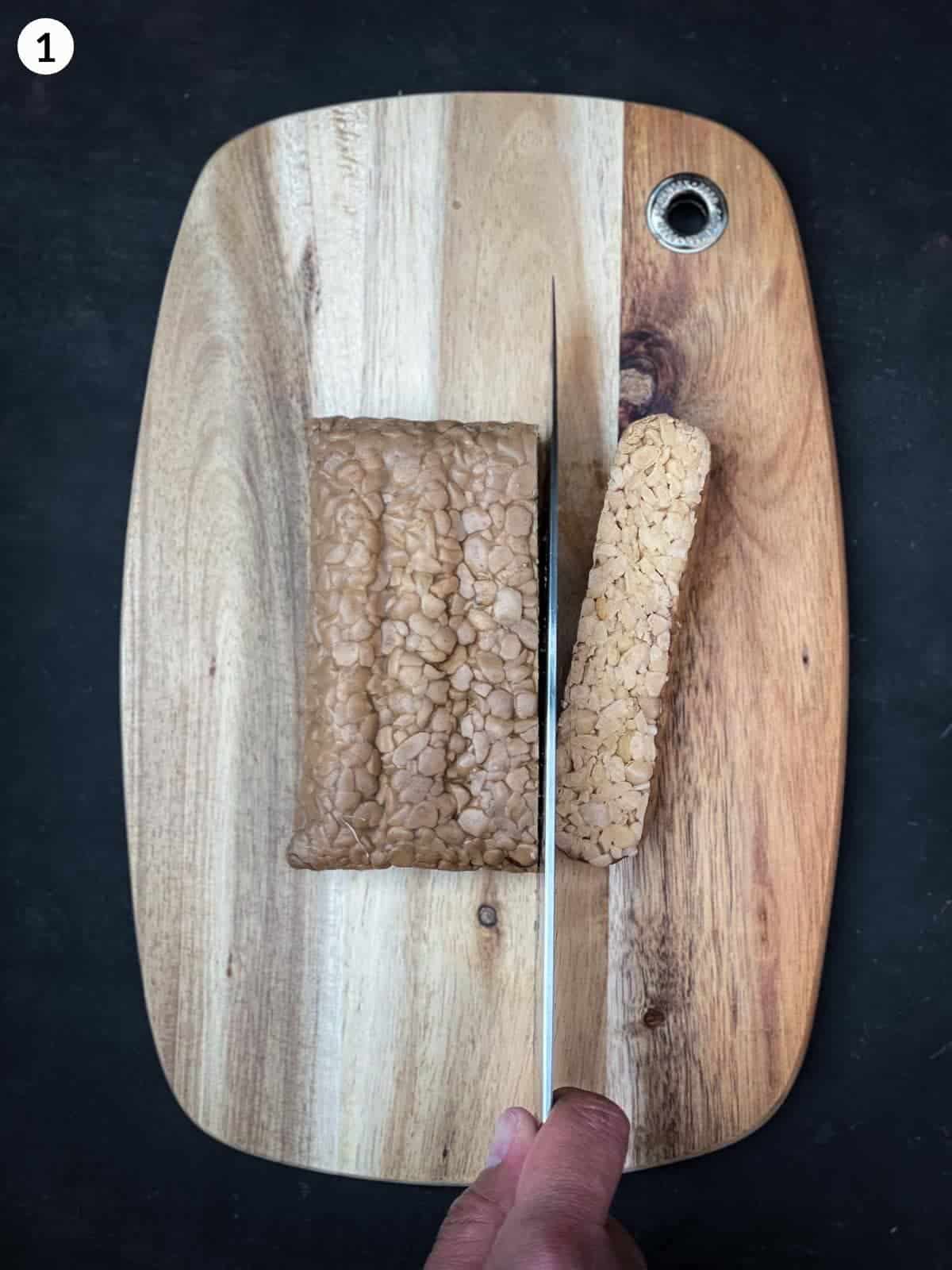 slicing tempeh with a knife on a wooden board