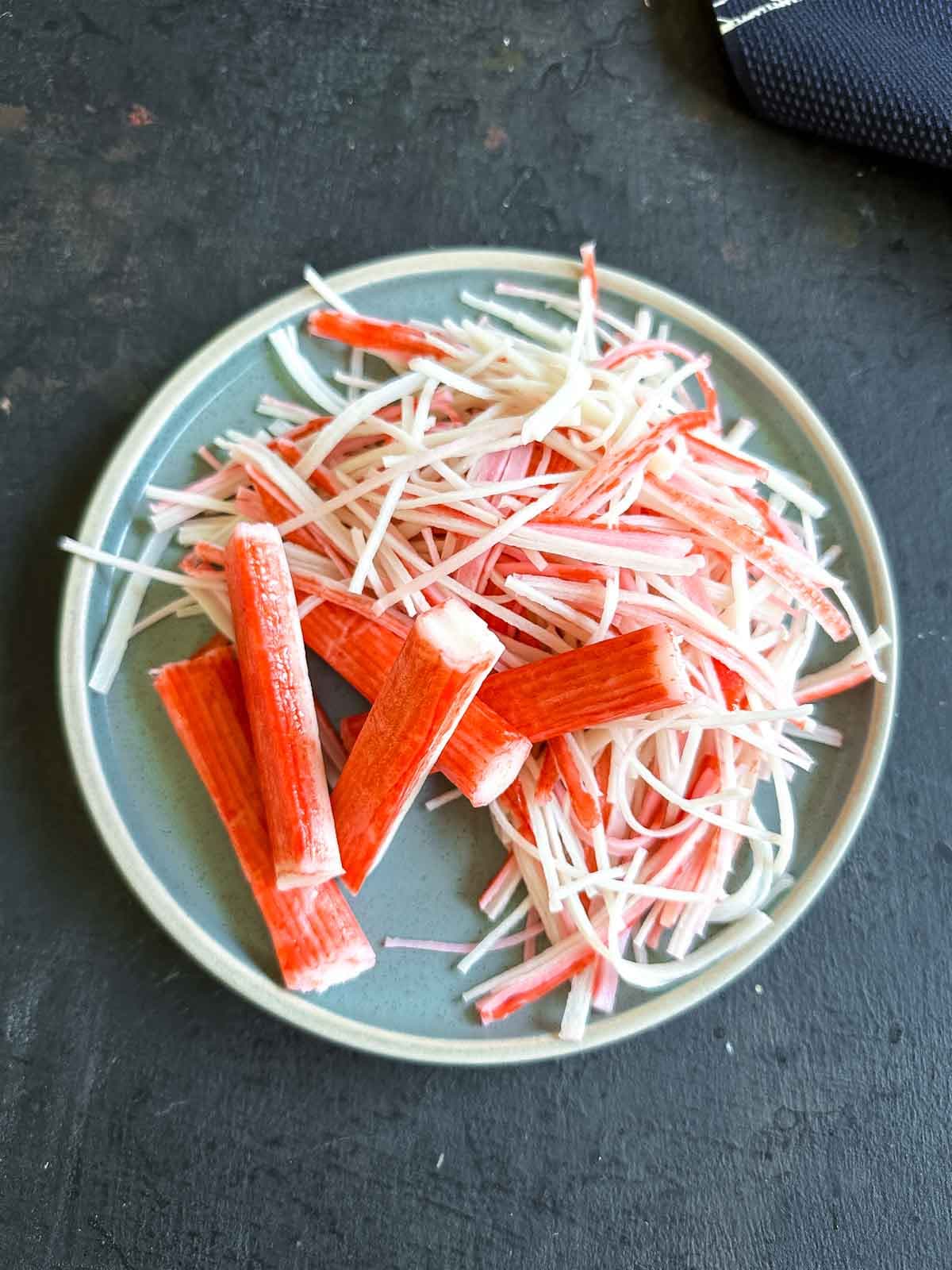 crab stick whole and shredded on a blue plate