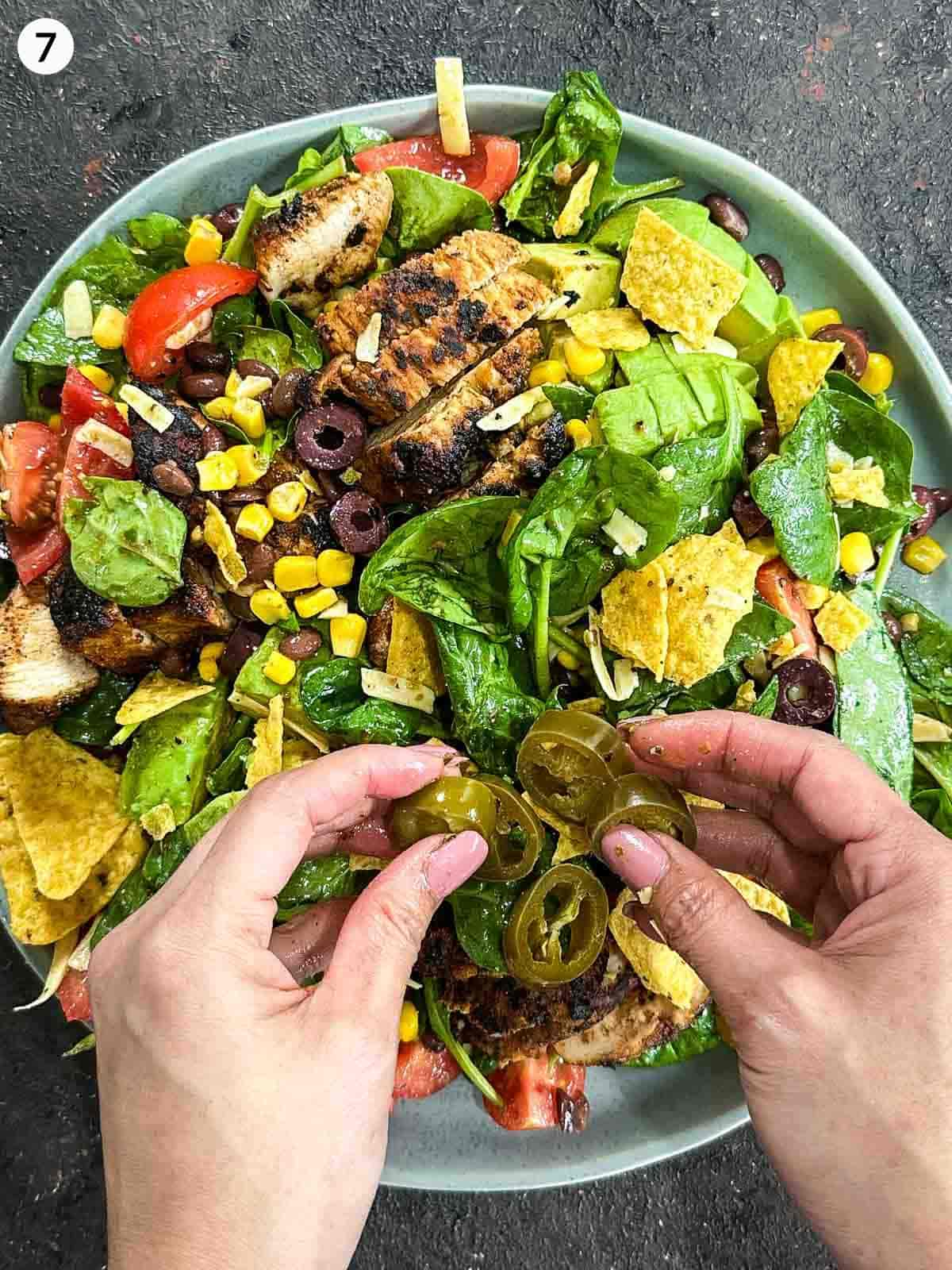 Adding jalapenos onto a plate of Santa Fe salad