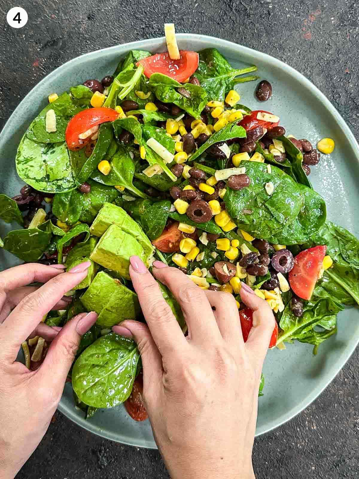 Adding avocado to a plate of Santa Fe salad