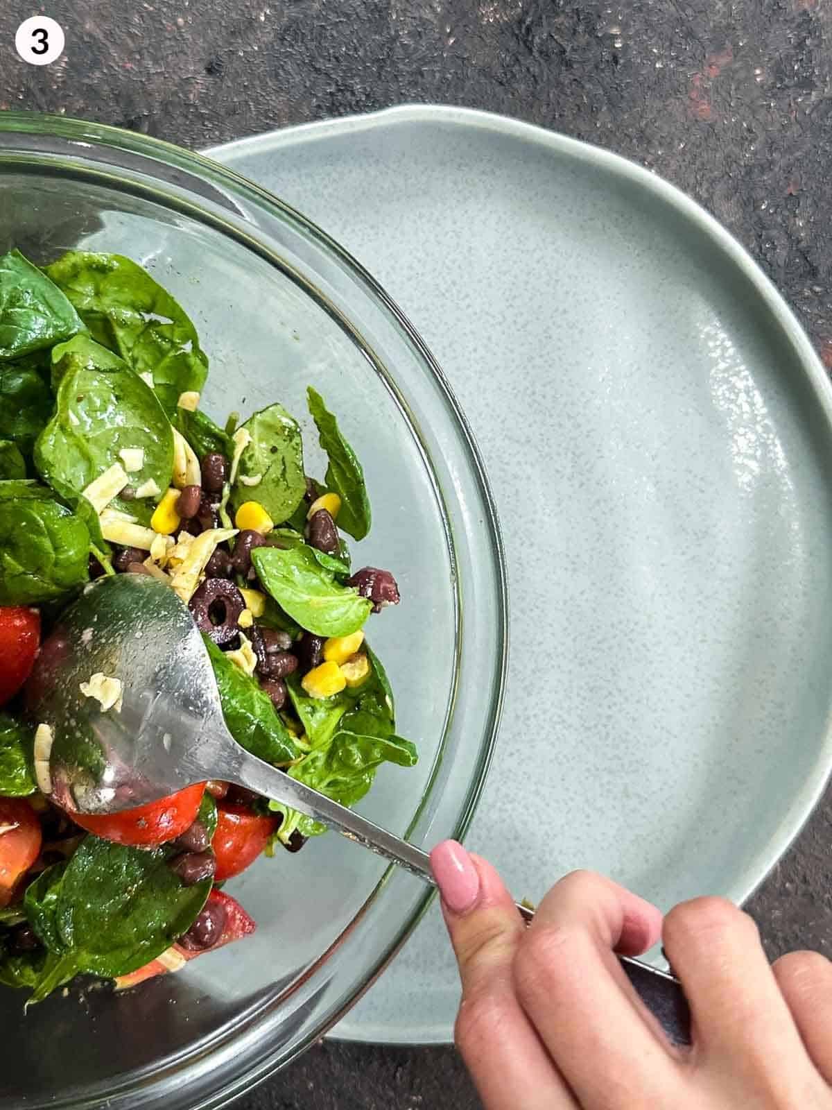 Pouring a mixing bowl of Santa Fe salad ingredients onto a green plate