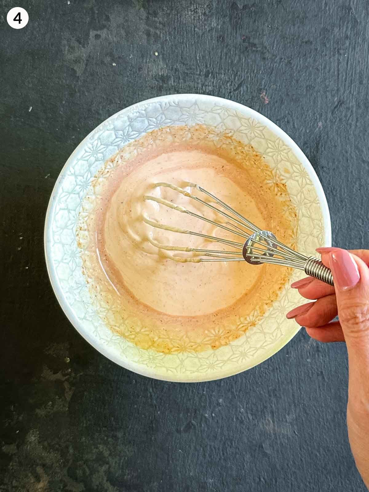 Mixing a creamy mayonnaise salad dressing in a white bowl